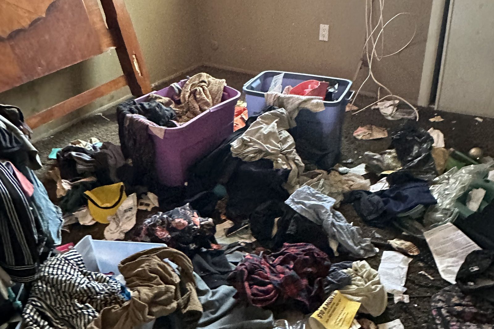 Bedroom covered in clothes and household items before a hoarding cleanup