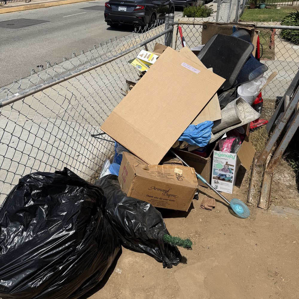 Furniture, boxes and bags piled by a fence for removal