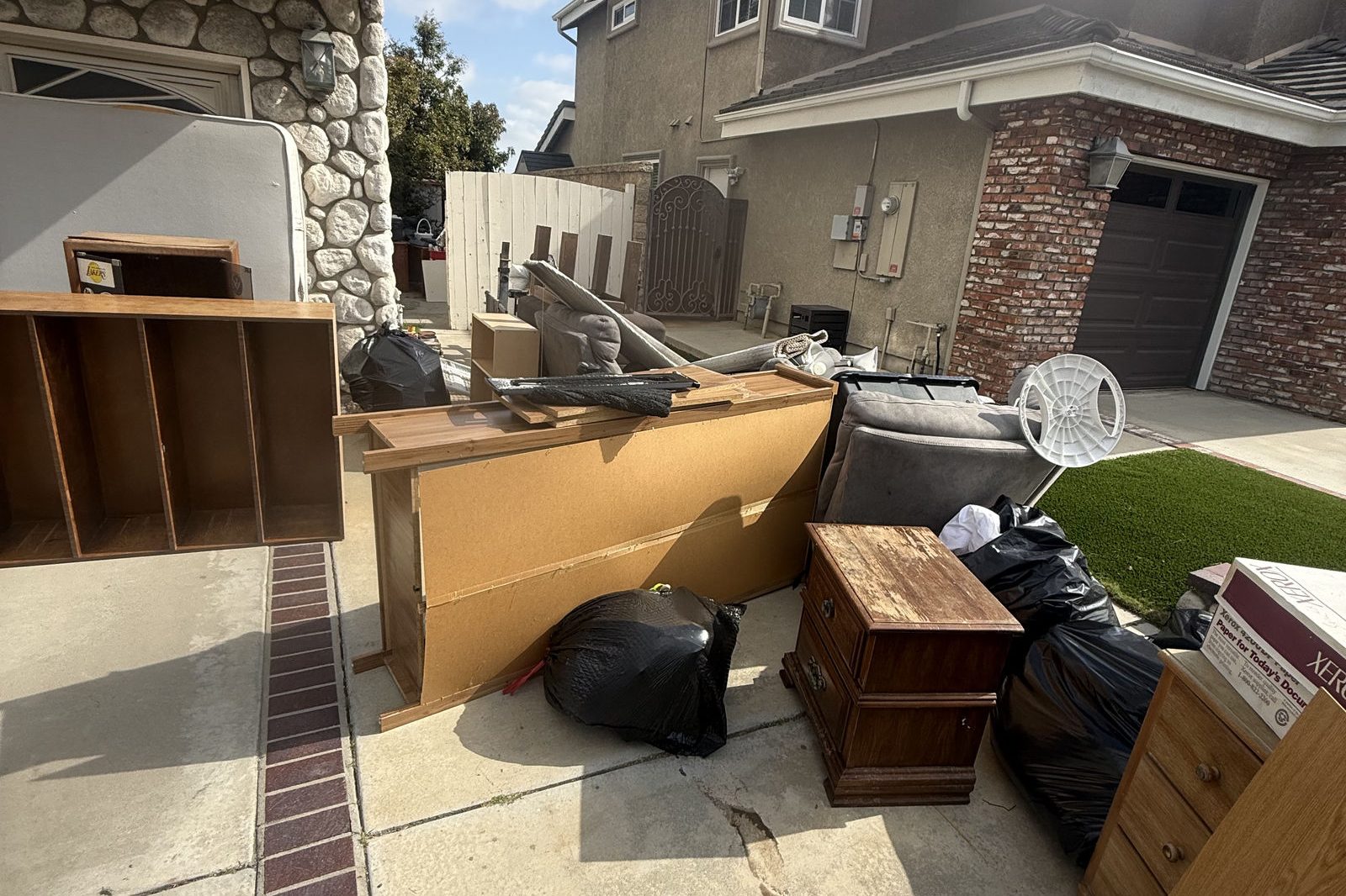 Old furniture and wood pieces piled up by a house, ready for pickup